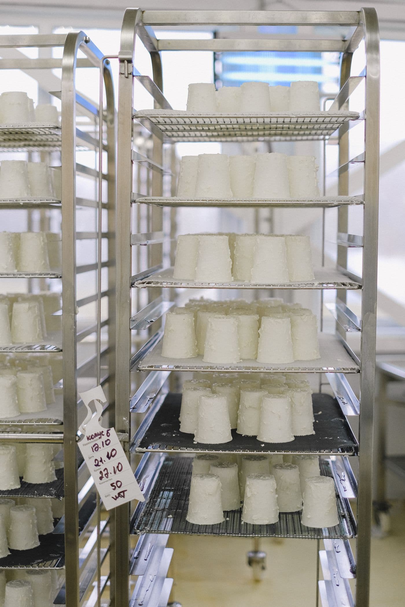 Fresh dairy products arranged on stainless-steel racks in a food-production facility